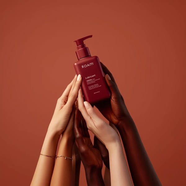Minimalist product photography of a matte red pump bottle labeled ‘ROAM lubricant’, held by multipl… prompt example