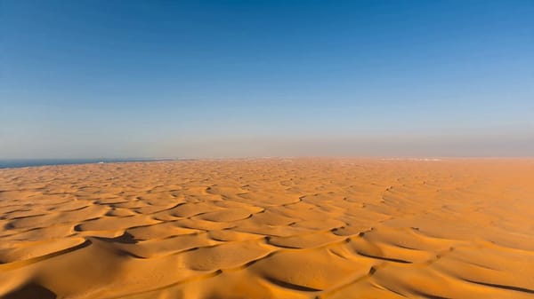 Cinematic timelapse sequence, 16:9, 15 seconds. Opens with a wide aerial shot of pure empty des…
