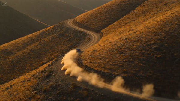 Ultra-cinematic 15-second rally car race through a rugged mountain dirt road during golden hour…