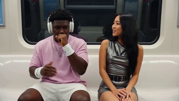 A dynamic, energetic music video-style scene set inside a brightly lit subway train car. The vi…