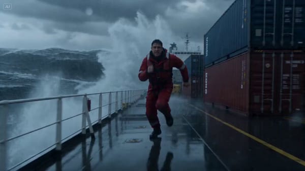 A man in his early 30s, dressed in a red rescue suit, runs along the deck of a huge cargo ship in t… prompt example