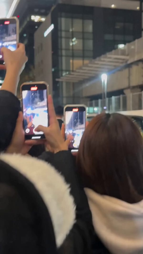 Style: Ultra-realistic mass celebrity arrival scene. Single continuous shot. Handheld camera fr…