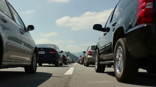 Ground-level chaos. Focus on one car escaping a Kaiju moving through traffic like a living bull…