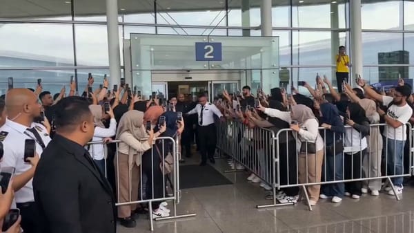 Style: Ultra-realistic mass celebrity arrival scene. Single continuous shot. Handheld camera fr…