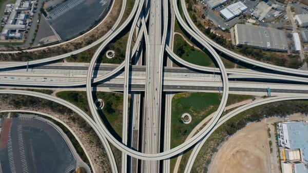 Rapid zoom down elevated freeways into a daylight cityscape with bending-perspective illusion (…