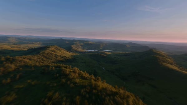 Epic ultra-wide aerial shot, pre-dawn sky transitioning from dark blue to pink at the horizon,…