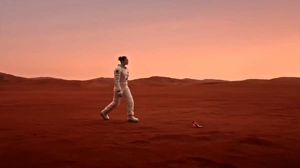 A lone female astronaut walks across a vast red desert beneath a beautiful pink sky. While expl…