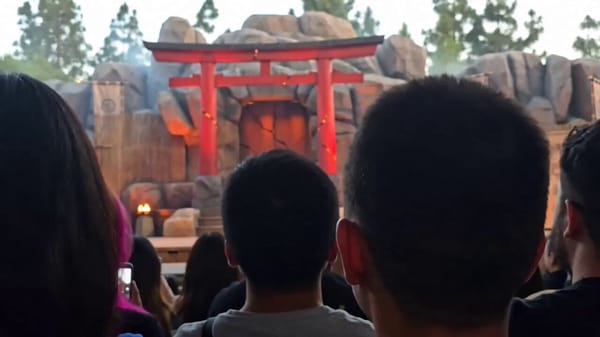 Audience-POV realistic smartphone video of an original fantasy outdoor stage performance. The f…