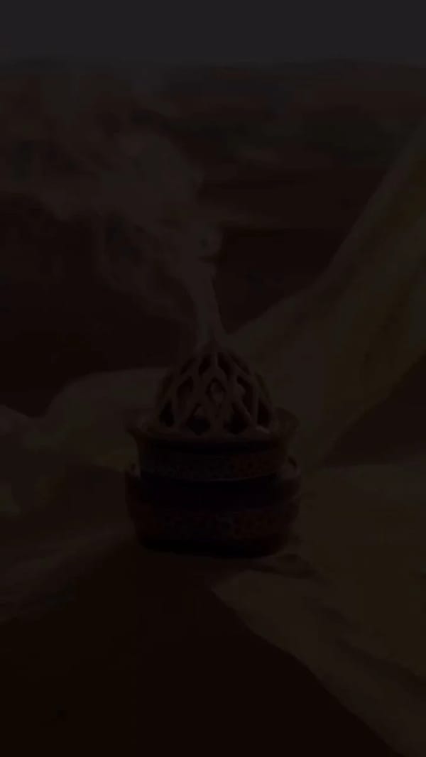 A cinematic desert journey at golden sunset, a mysterious woman wrapped in flowing translucent fabr… prompt example