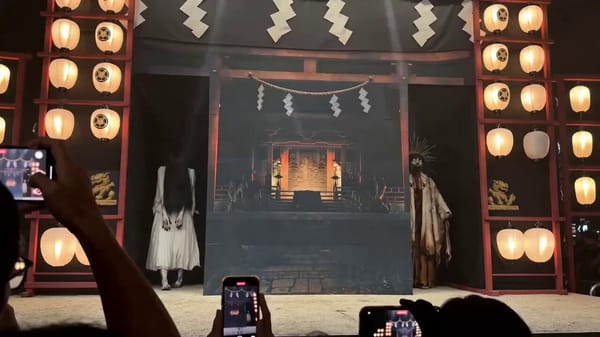 Japanese night festival, audience-recorded iPhone footage, traditional outdoor stage surrounded by… prompt example
