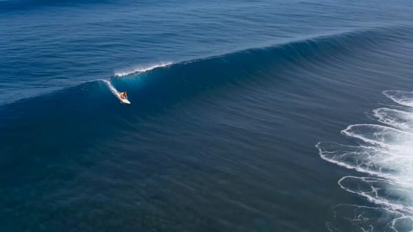 Cinematic commercial wide shot, a determined young woman with vibrant red hair surfing on a pow…