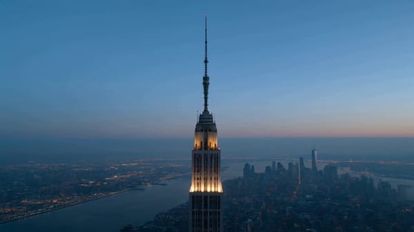 Main Subject: Two elite urban climbers standing on the upper spire of Empire State Building, ~1…
