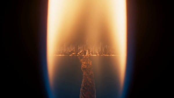 Extreme macro shot of a single candle flame burning in a dark room. The background is black, si…