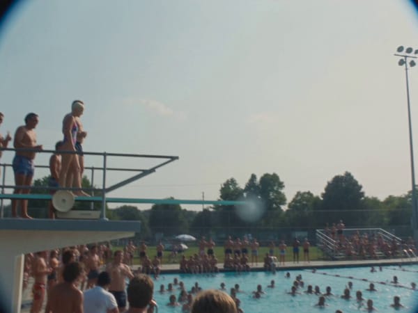 This is real 1990s home video footage shot on a VHS camcorder at a crowded public swimming pool…