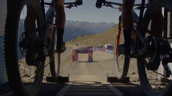 Ultra-photorealistic cinematic vertical video of an Olympic-level mountain-bike final featuring…