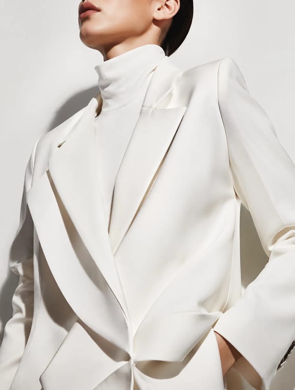 A sophisticated editorial portrait of a model wearing an architectural ivory-white avant-garde…